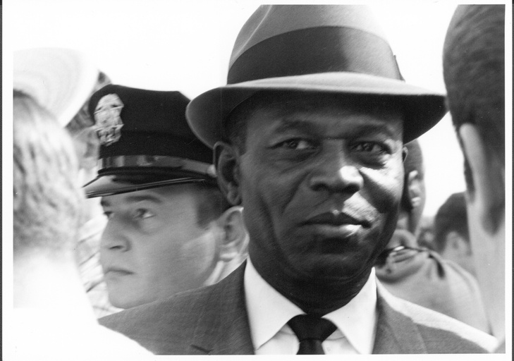 Close-up of an African-American man with a white police office standing behind him at the Wallace-for-president rally in Durham.