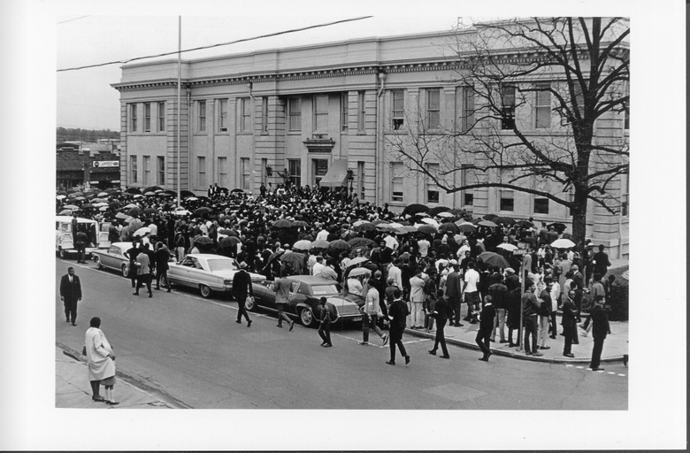 A large crowd of people gathered outside of city hall.