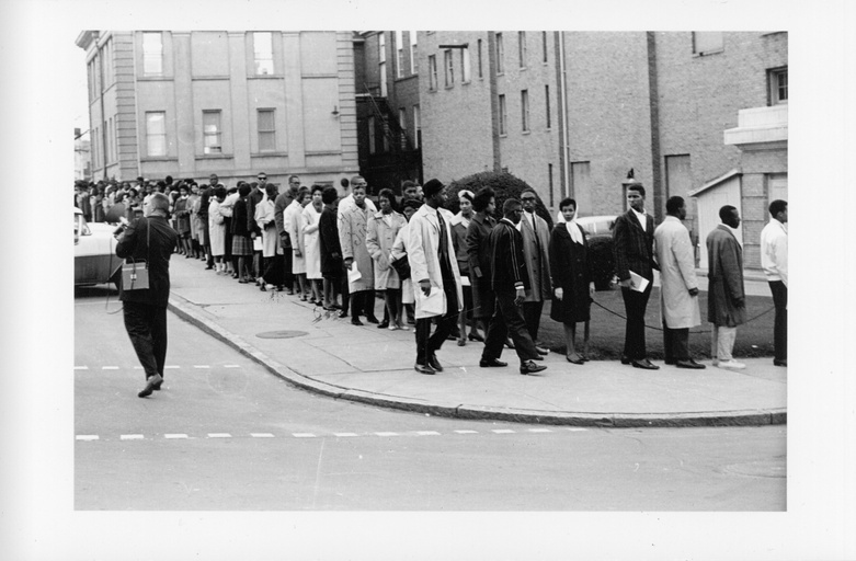 A long line of black people formed along a sidewalk outside the Carolina Theatre.