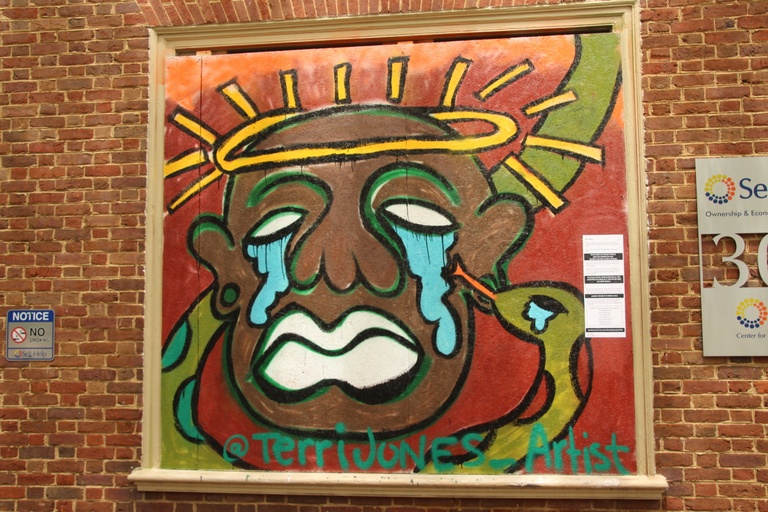 An image of a black man with a halo and tears pouring out of his eyes with a snake pictured around him, also crying.